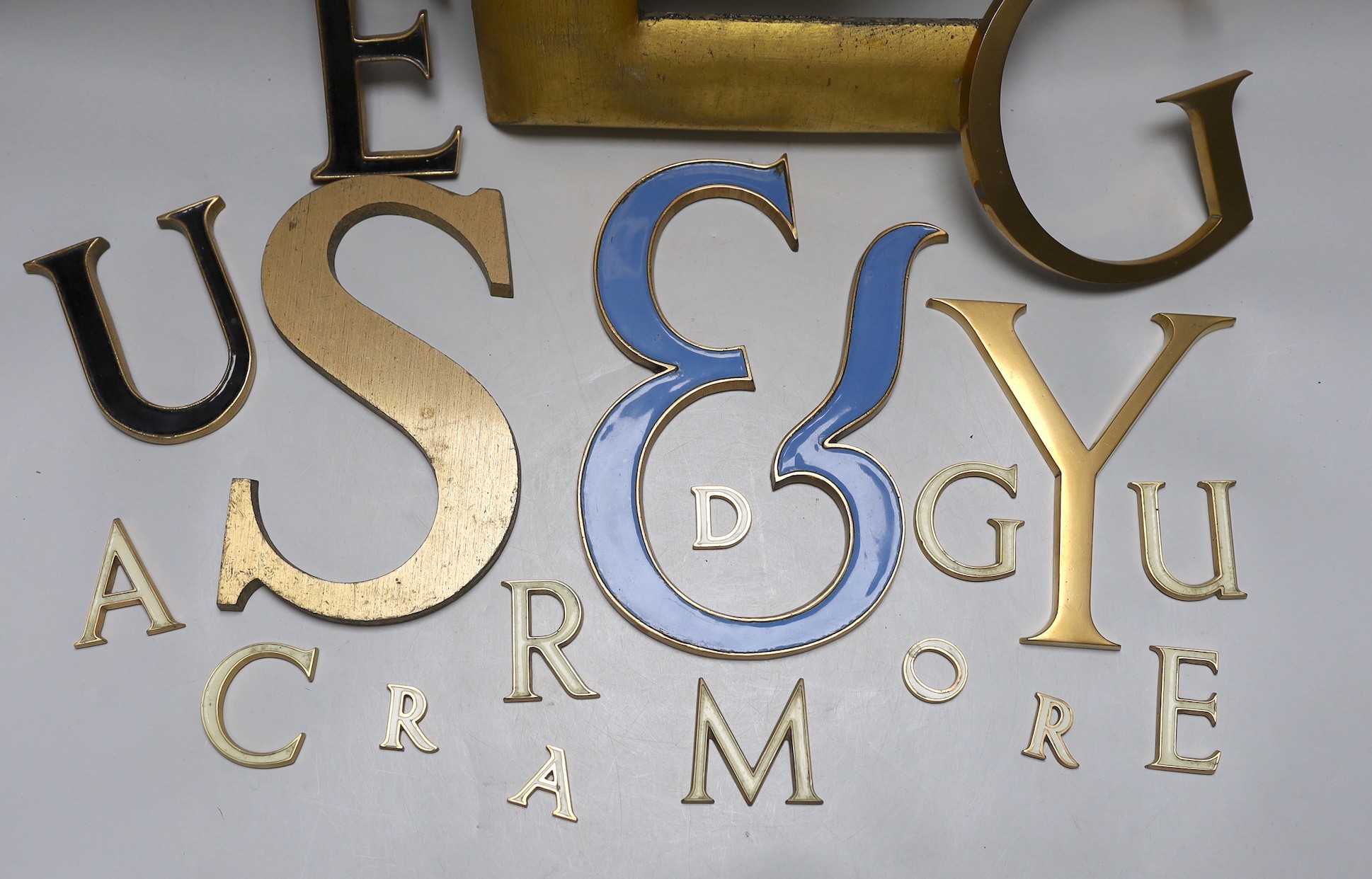A collection of brass and enamelled lettering of varying sizes and fonts